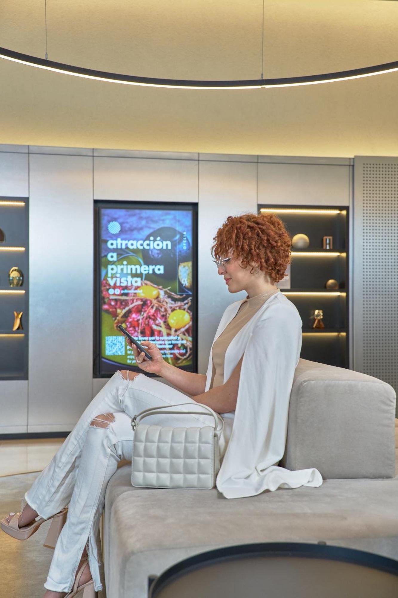 Pullman Santiago Vitacura Экстерьер фото A woman using a mobile phone to interact with a digital signage display